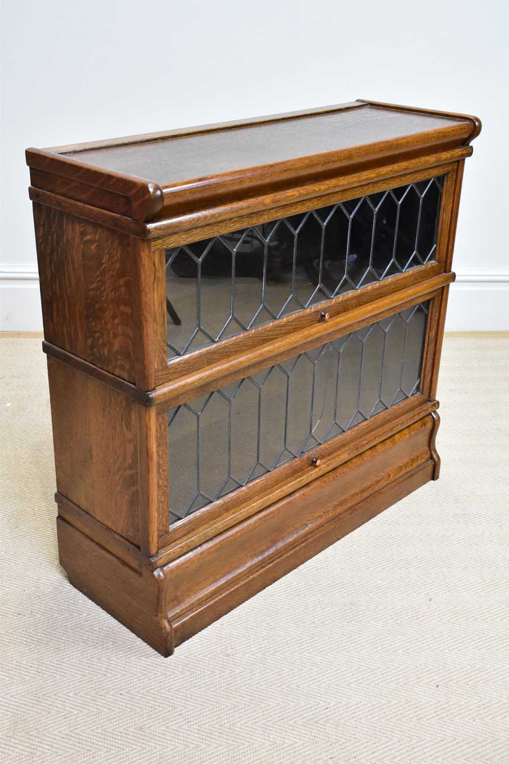 GLOBE WERNICKE; an oak two tier metal bound stacking bookcase with leaded glazed up and over door,