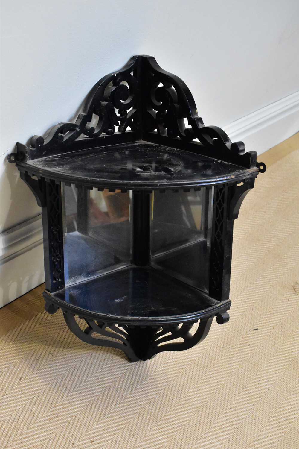 A Victorian ebonised corner shelf with mirrored back and pierced decoration, height 58cm.