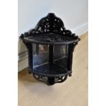 A Victorian ebonised corner shelf with mirrored back and pierced decoration, height 58cm.