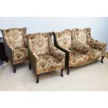 An Edwardian three piece lounge suite comprising a two division wingback sofa and two matching