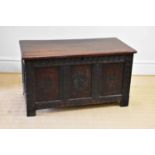 An 18th century and later oak coffer with replacement top and carved and panelled front, on block