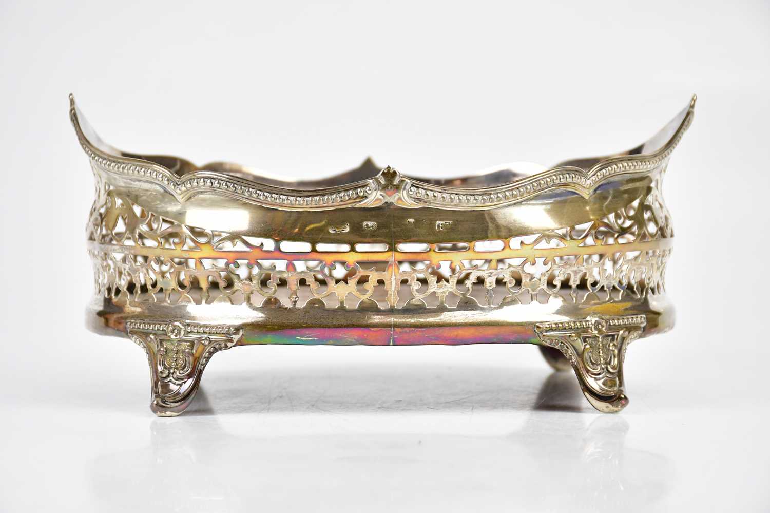 A Victorian hallmarked silver oval condiment stand, with pierced border, on scrolling legs,