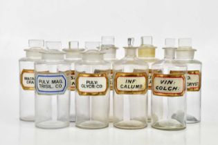 A collection of Victorian clear glass pharmaceutical bottles with glass labels, various names