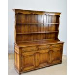 A reproduction oak dresser with boarded plate rack back above the base section with three drawers