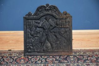 A cast iron fireplace rear plate/fire back decorated with a blacksmith.
