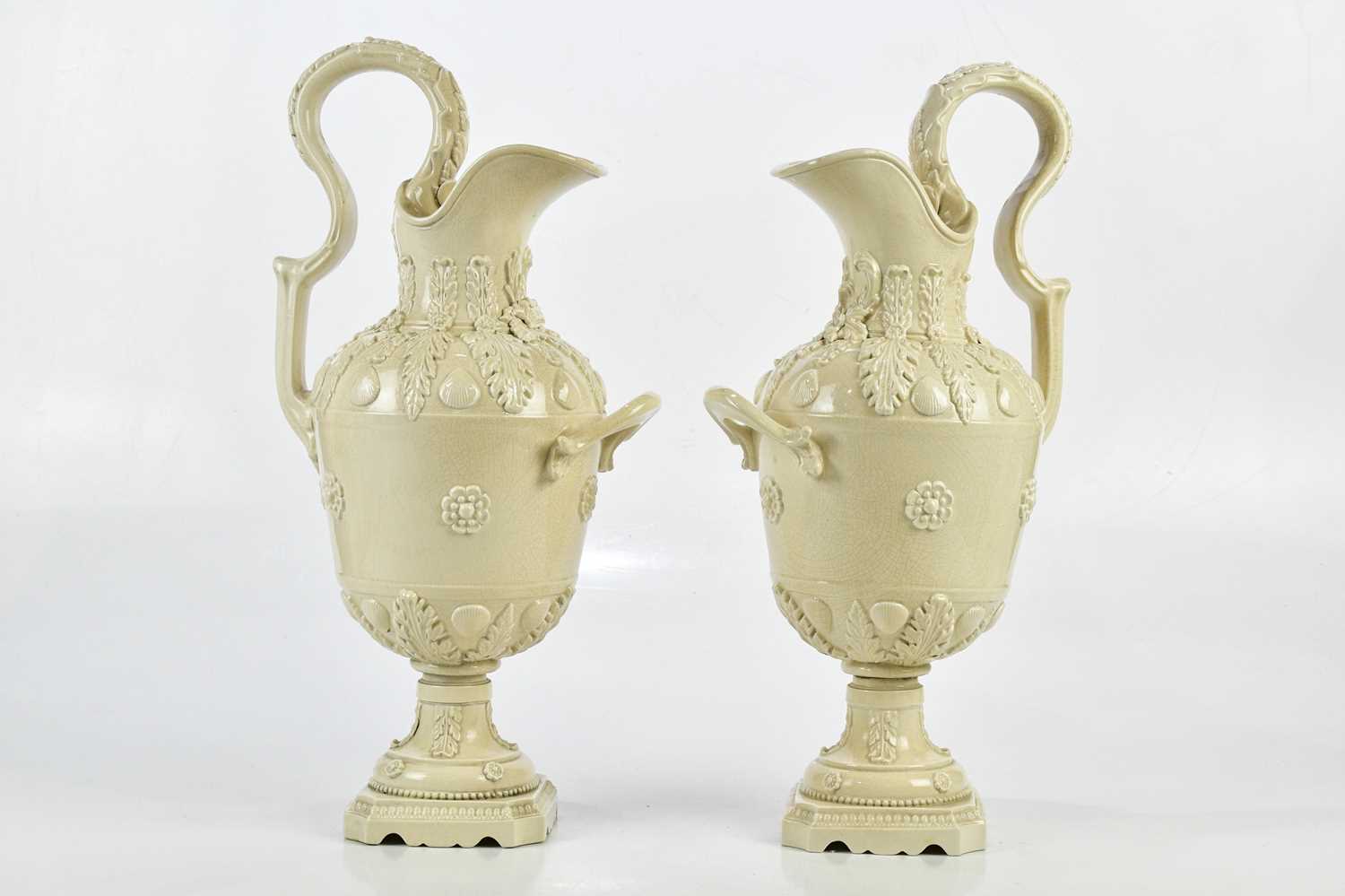 PETER WELDON; a pair of crackle glazed ewers, relief decorated with shells and floral detail, height