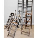 A collection of vintage wooden folding and step ladders.