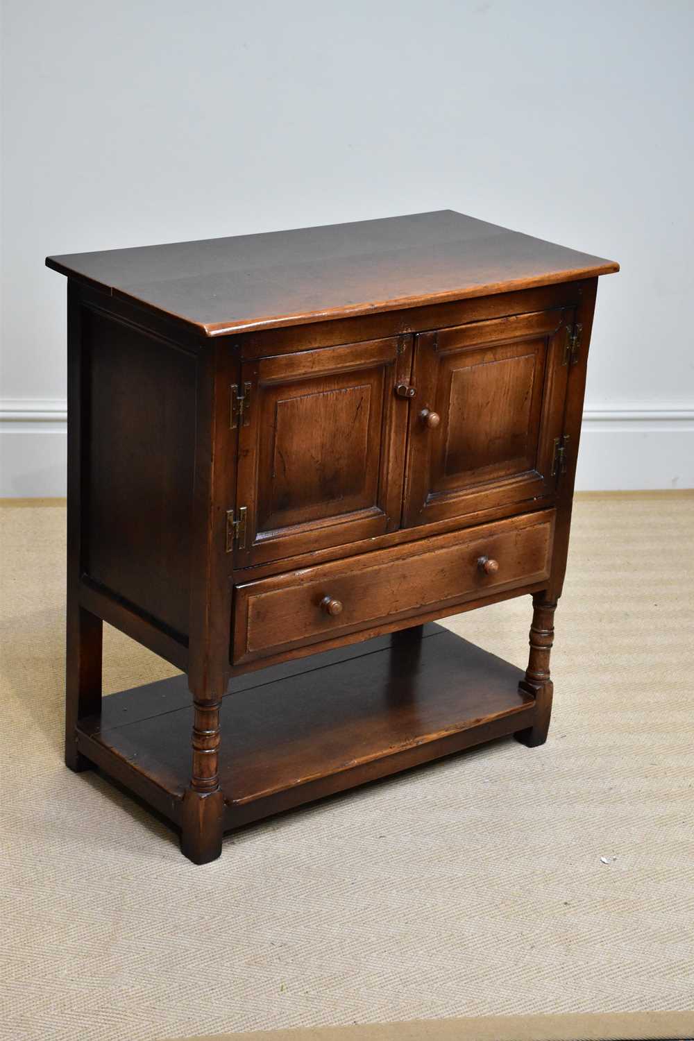 A reproduction oak side cabinet, with two panelled doors above single drawer and undertier, width