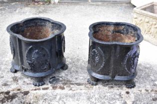 A pair of cast iron planters, both raised on four feet, height 26cm, diameter 30cm.