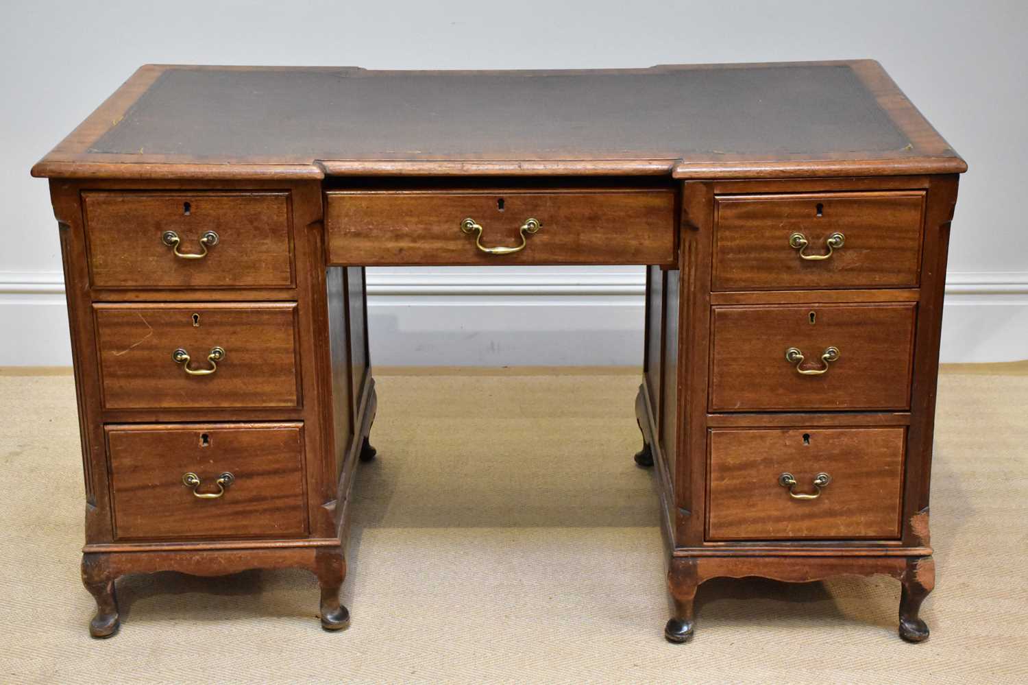 A late 19th century inverted breakfront kneehole desk with leather inset top above an arrangement of