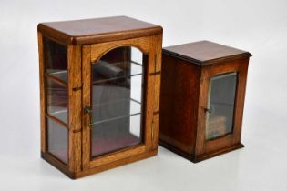 An early 20th century oak smoker's cabinet with single glazed door containing two pipes and an oak