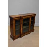 A Victorian breakfront walnut credenza, with three glazed doors enclosing shelves, on bracket