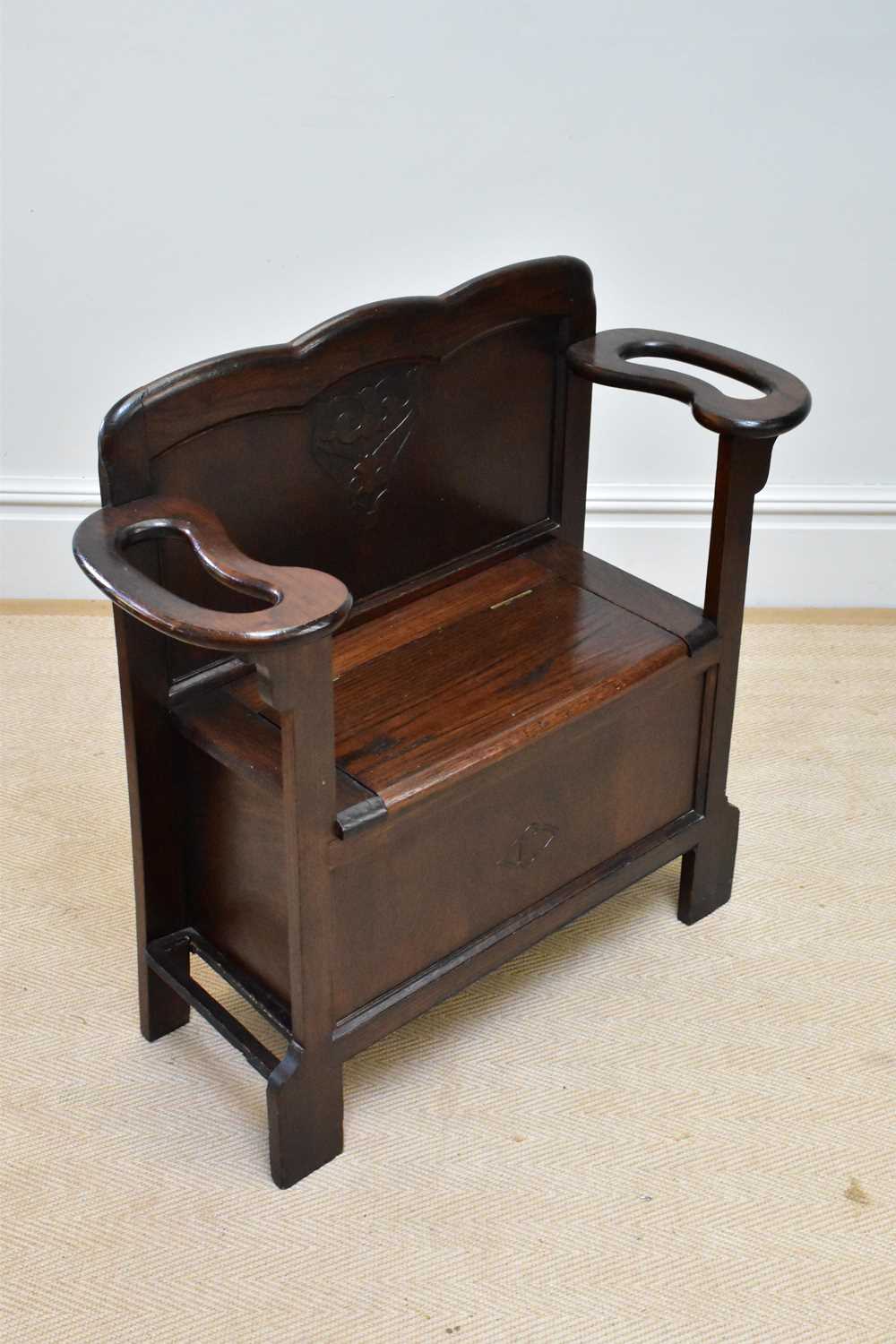 An early 20th century oak settle/stick stand with hinged seat, width 82cm.