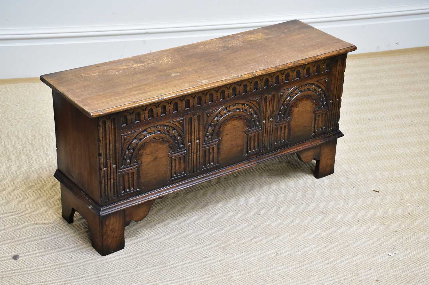 A reproduction oak blanket chest with carved and panelled front, on block legs, width 99cm, depth