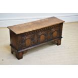 A reproduction oak blanket chest with carved and panelled front, on block legs, width 99cm, depth