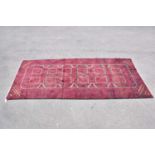 A red ground wool carpet with geometric central pattern, 295 x 130cm.