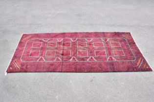 A red ground wool carpet with geometric central pattern, 295 x 130cm.