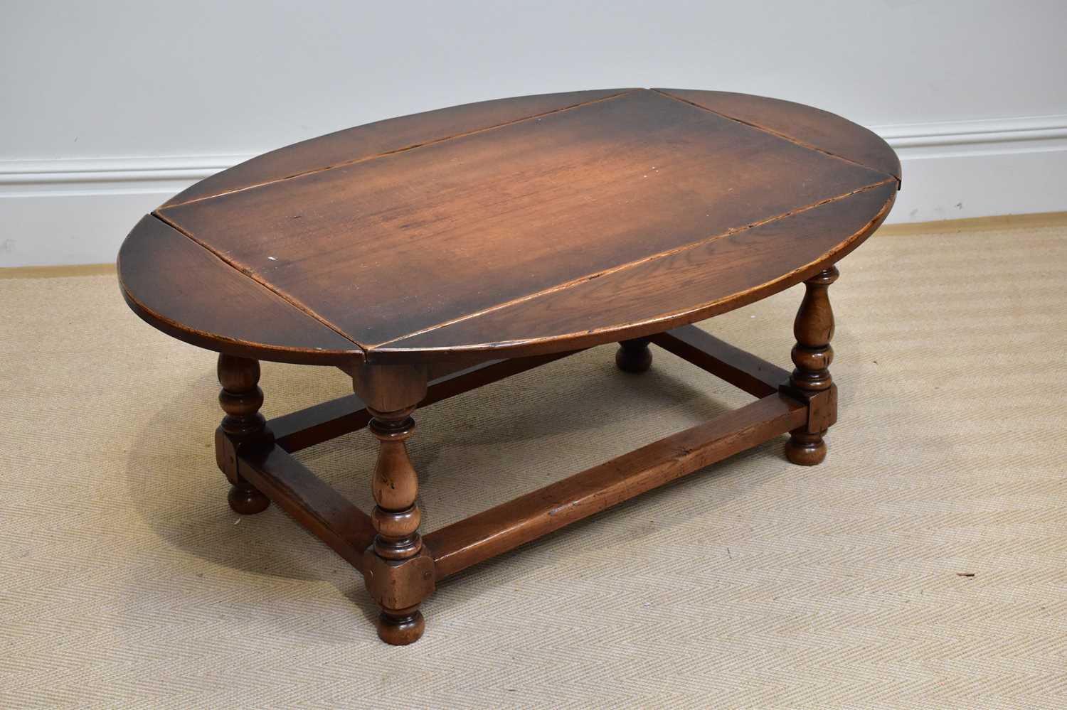 A reproduction oak drop-leaf coffee table of rectangular form, on bun feet, width 95cm, height