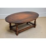 A reproduction oak drop-leaf coffee table of rectangular form, on bun feet, width 95cm, height