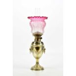 A Victorian silver plated oil lamp with clear glass chimney and cranberry shade, height 60cm.