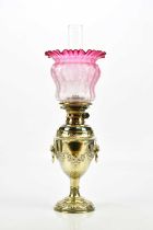 A Victorian silver plated oil lamp with clear glass chimney and cranberry shade, height 60cm.