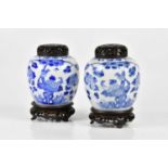 A pair of late 19th century Chinese blue and white ginger jars with carved wooden covers, each