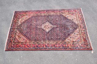 An orange ground carpet with central geometric pattern, 204 x 135cm.
