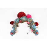 A Chinese Peking opera headdress with applied turquoise silk and jewelled decoration.