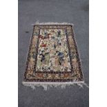 An Eastern style part silk rug decorated with figures on horseback hunting on an ivory ground,