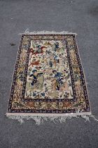 An Eastern style part silk rug decorated with figures on horseback hunting on an ivory ground,