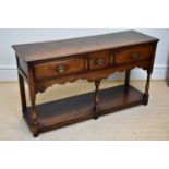 A reproduction oak dresser base, with three drawers and undertier, on block feet, width 136cm, depth