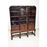 An early 20th century mahogany three door display cabinet, on turned columns terminating on bun