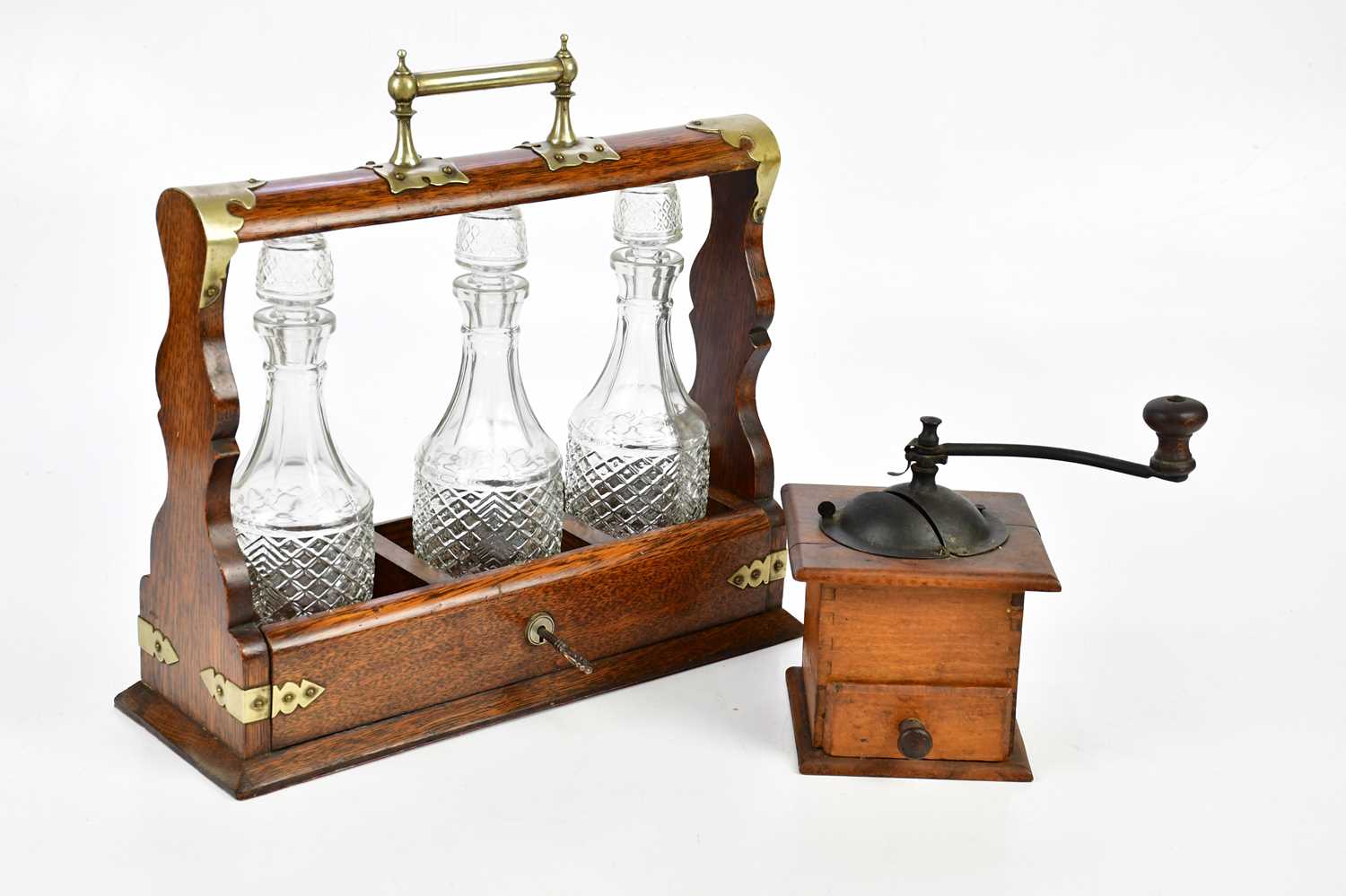 An early 20th century oak tantalus with silver plated mounts, housing three associated moulded glass
