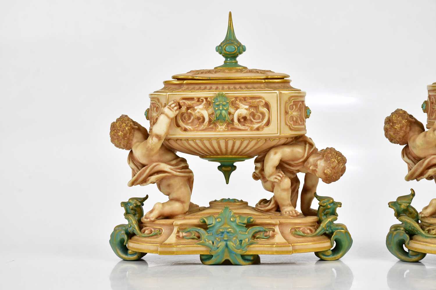 ROYAL WORCESTER; a pair of unusual lidded urn vases of oval form, the urns supported by cherubs on a - Image 2 of 6