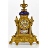 A 19th century French ormolu and porcelain mantel clock with twin handled urn finial above the