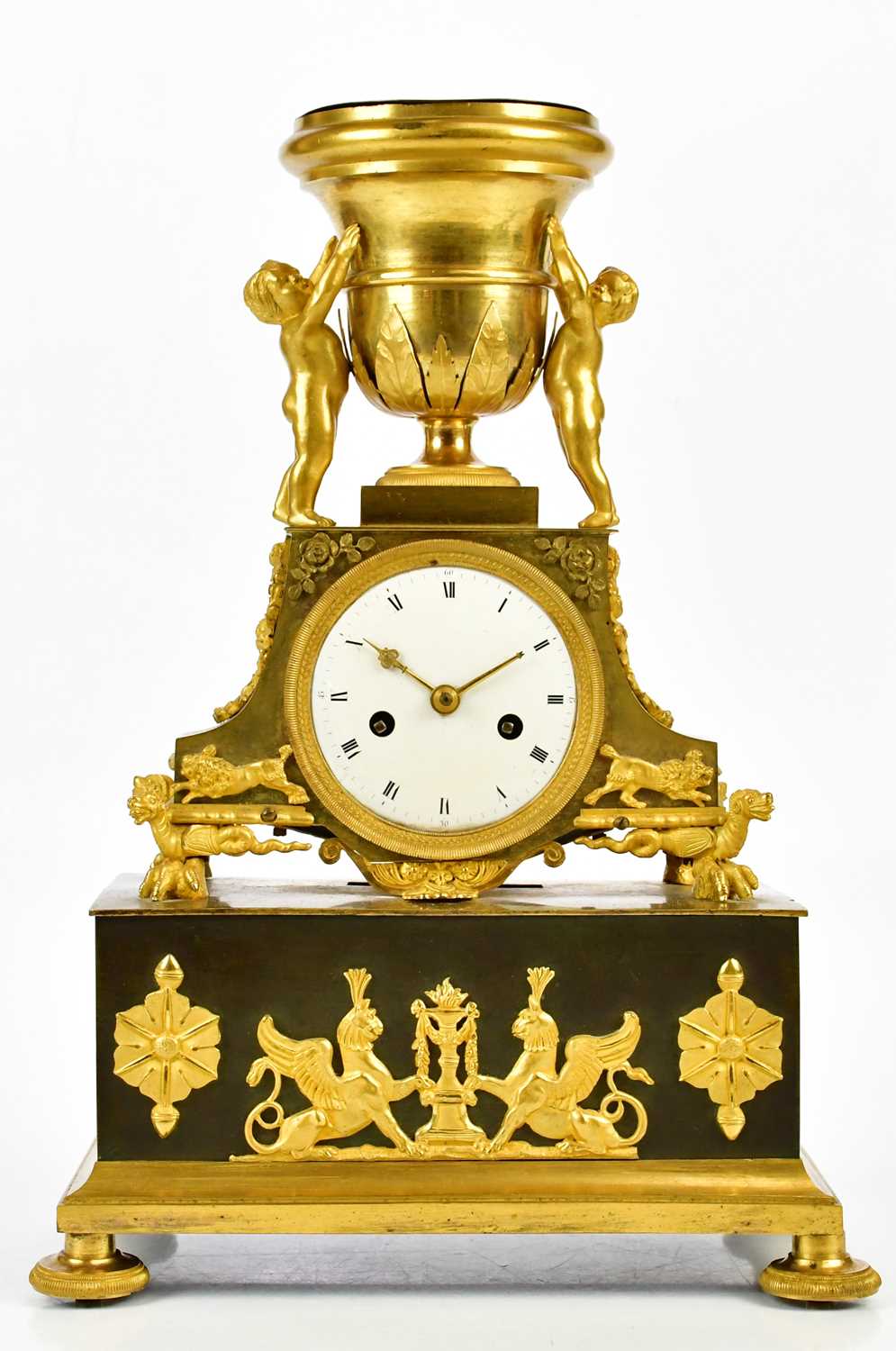 A late 19th century French ormolu mantel clock with cherubs supporting an urn finial above the