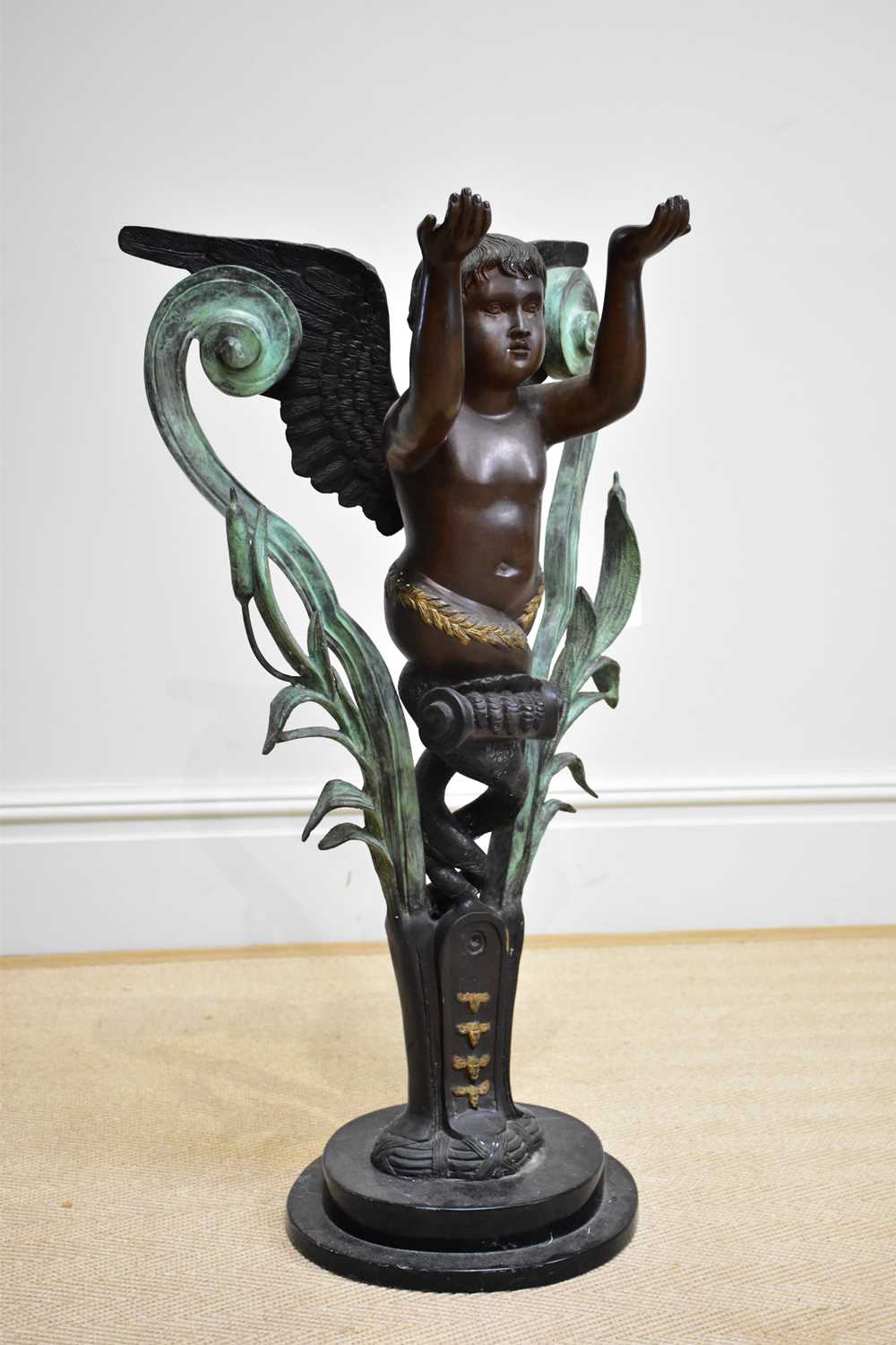 A modern decorative patinated metal figure of a standing cherub on marble base, height 90cm.