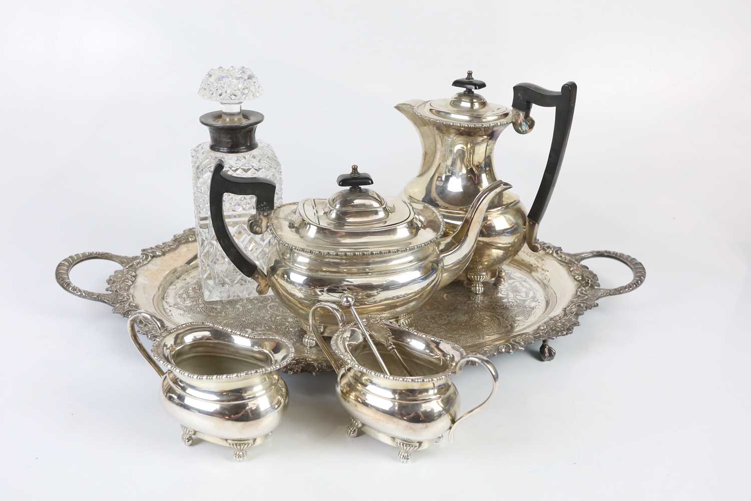 A silver plated four piece tea service with twin handled tray and cut glass decanter.
