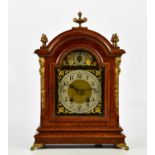 An early 20th century oak mantel clock with applied brass urn finial and four further scrolling