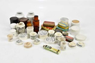 A collection of pharmaceutical related items including pot lids, ointment pot, black and white