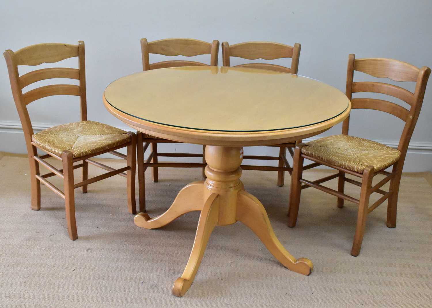 A modern kitchen table with four rush seated chairs.