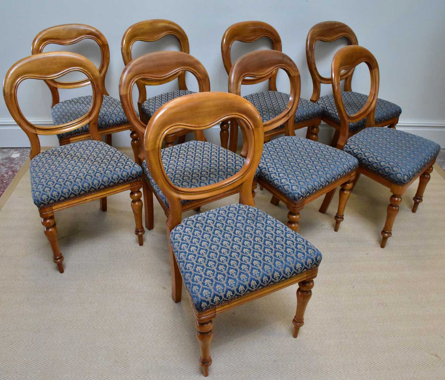 A set of nine Victorian balloon back dining chairs on turned column supports.