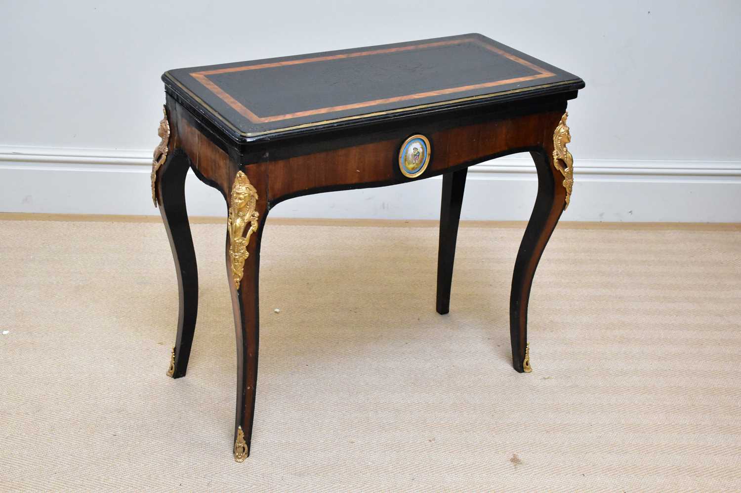 A 19th century ebonised and rosewood gilt metal mounted fold-over games table, with porcelain oval