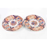 A pair of early 20th century Japanese Imari wall chargers with scalloped edges, decorated to the