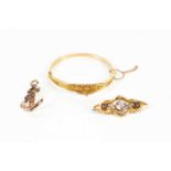 A 9ct gold hinged snap bangle with cast floral decoration, a Victorian 9ct gold brooch set with