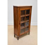 A 1930s oak display cabinet, with glazed door enclosing shelves, on turned legs, height 141cm, width