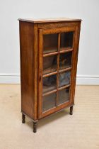 A 1930s oak display cabinet, with glazed door enclosing shelves, on turned legs, height 141cm, width