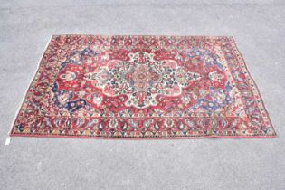 A red ground wool carpet with geometric central design, 224 x 140cm.