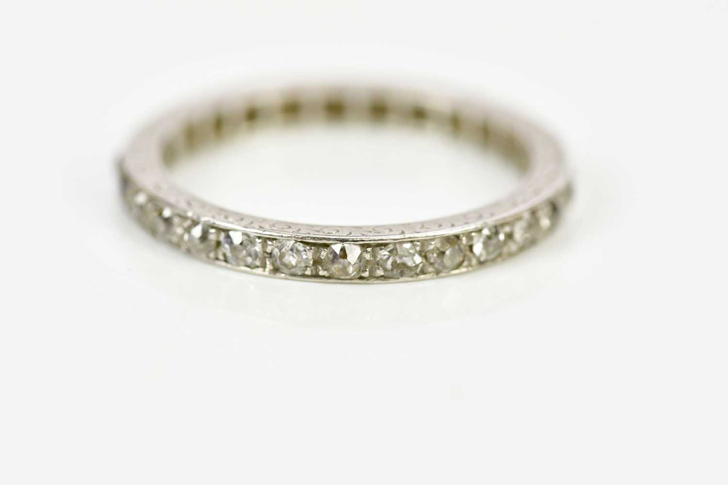 An early 20th century platinum and diamond full eternity ring with engraved detail, size M, approx