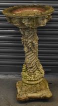 A 20th century composite stone bird bath with column base decorated with scrolling fruit and